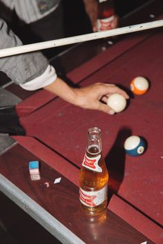 a bottle of beer sitting on top of a table next to ping pong balls