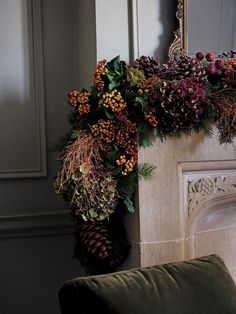 a fireplace decorated with greenery and pine cones