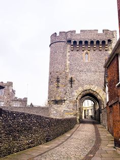 an old brick castle with a stone walkway leading to the entrance and another building in the background