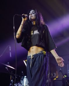 a woman standing on top of a stage holding a microphone in her hand and singing