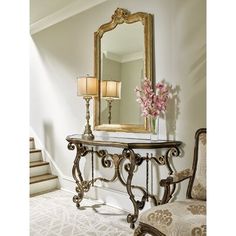 an ornate console table with two lamps and a mirror on it in a white room