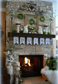 a fireplace decorated for spring with white flowers and greenery on the mantel above it