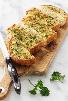 two pieces of bread on a cutting board with a knife and parsley next to it