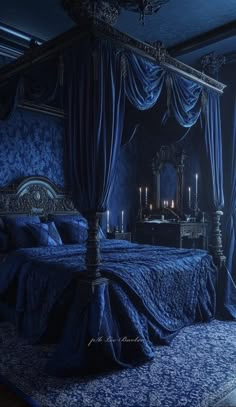 a bed with blue sheets and drapes in a room that is lit by candles