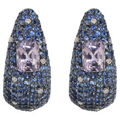 Introducing our Victorian 8.00 Cttw. Blue Sapphire, Spinel, and Diamond Hook Stud Earrings – a captivating fusion of elegance and sophistication. These stunning stud earrings boast a unique curved design, adorned with a dazzling array of round blue sapphires meticulously set in black prongs. The sapphires cascade along the front of the earrings, interspersed with shimmering diamonds that add an extra layer of sparkle and brilliance to the piece. At the heart of each earring lies a mesmerizing cu Blue Diamond Earrings For Evening, Blue Pave Set Earrings For Formal Occasions, Formal Blue Pave Set Earrings, Luxury Tanzanite Earrings, Blue Diamond Earrings With Pave Setting, Luxury Tanzanite Gemstone Earrings, Luxury Tanzanite Earrings With Gemstone, Blue Multi-stone Cubic Zirconia Earrings, Blue Cubic Zirconia Earrings With Pave Setting