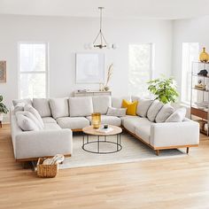 a living room with white walls and wooden floors is furnished with modern furniture, including a large sectional sofa