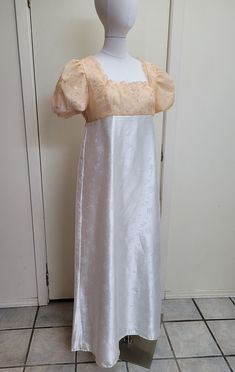 This dress has tracked shipping included within the US and Canada!    We offer a basic Regency styled gown, with the empire waist and short puffed sleeves.  The top of this dress has an apricot pink sheer overlay that has been embroidered with a scrolling design and tiny sequins.  The neckline has been trimmed with lace.  The skirt of the dress is a white satin jacquard with a dainty floral design.  Please check teh waist to hem measurement, as this is hemmed to a petite length.    *This gown ti Regency Style Fitted Evening Dress, Regency Style Empire Waist Evening Gown, Fitted Floor-length Maxi Dress For Fancy Dress, Fitted Empire Waist Evening Gown, Empire Waist Fitted Gown For Evening, Fitted Empire Waist Gown For Evenings, Regency Style Fitted Formal Gown, Cream Full-length Formal Dress, Formal Regency Style Fitted Gown