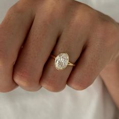 a woman's hand with a diamond ring on her finger, showing the center stone