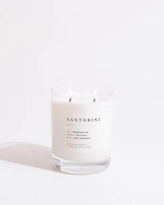 a white candle sitting on top of a table next to a glass container filled with candles