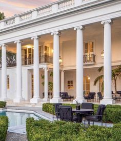 a large white house with columns on the front and an oval pool in the middle