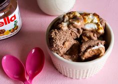 a bowl filled with ice cream next to two spoons and a jar of peanut butter