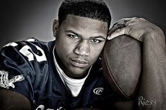 a black and white photo of a football player with his arm resting on the ball