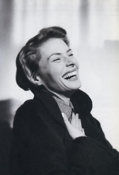 a woman with her eyes closed and mouth wide open, laughing while wearing a black coat