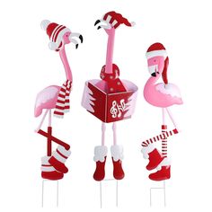 three flamingos are standing next to each other in christmas hats and stockings on sticks