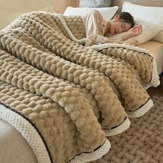 a woman laying on top of a bed under a blanket