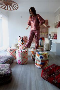 a woman in pink pajamas standing on top of some colorful poufce stools