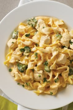 pasta with chicken and broccoli in a white bowl on top of a green napkin