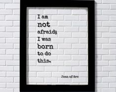 a white brick wall with a black frame hanging on it's side that says, i am not afraid i was born to do this