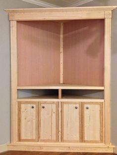 a wooden bookcase with two doors and three cupboards on the bottom, in front of a gray wall