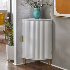 a white cabinet sitting next to a wall with a blue vase on top of it