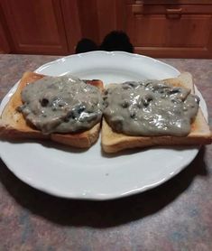 two pieces of bread with gravy on them sitting on a plate in the kitchen