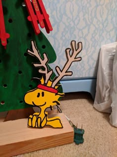 a wooden cutout of a cartoon character in front of a christmas tree