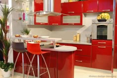 a kitchen with red cabinets and stools in front of a stove top oven next to a potted plant