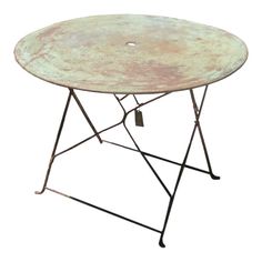 a round table with metal legs and an iron frame on the top, against a white background