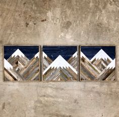 three pieces of wood with mountains in them on a concrete wall next to each other