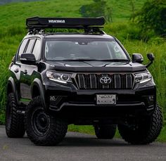 a black four - doored suv parked on the side of a road in front of green grass