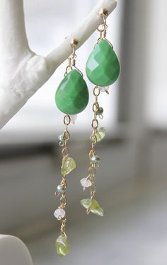 Green-colored quartz earrings with catchers holding a 14k gold-filled chain strung with tumbled peridot (3 per earring), moonstone (2 per earring) and green freshwater pearl (2 per earring).  Also comes with a pair of rubber ear nuts for another simple look. All wire used is 14k gold-filled. Green-colored quartz size: 10mm/0.4in x 13mm/0.5in Freshwater pearl size: 3mm/0.12in Tumbled Peridot size: 5mm/0.2in x 7mm/0.28in Moonstone size: 4mm/0.16in x 2mm/0.08in Length of earring: 6.6cm / 2.6in Hand Green 14k Gold-filled Dangle Earrings, Green 14k Gold Filled Dangle Earrings, Yellow Gold Jade Dangle Jewelry, Green Peridot Drop Earrings, Handmade Green Briolette Jewelry, Green May Birthstone Long Drop Jewelry, Handmade Peridot Dangle Jewelry, Green Peridot Wire Wrapped Jewelry, Wire Wrapped Dangle Jewelry For May Birthstone