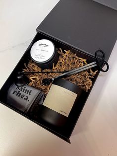 an open box with scissors, shaving brush and other items in it on a table