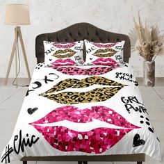 a bed with pink and gold lipstick on the sheets, pillows and pillow cases in front of a white wall