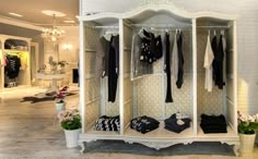 a white closet filled with lots of black and white clothing hanging on it's walls