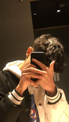 a man taking a selfie in the mirror with his cell phone while wearing a jacket