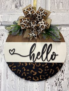 a leopard print door hanger with the word hello written on it and a bow