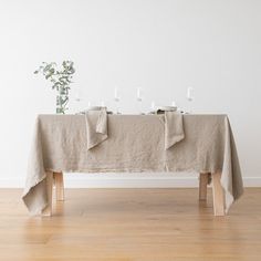 the table is set with four candles and two vases on each side, along with some flowers