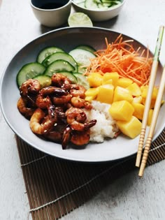 a white plate topped with shrimp, rice and veggies next to chopsticks