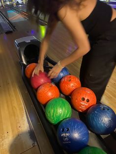 a woman is picking up her bowling balls