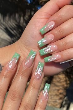 a woman's hand with green and white nail designs on it, holding her hands out