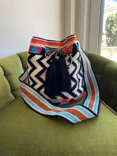 a multicolored bag sitting on top of a green couch next to a window