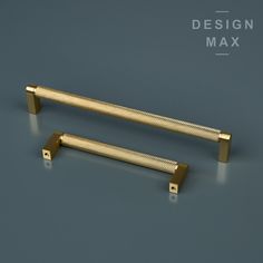 two golden handles on a gray surface with the words design max in gold letters above them