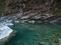 the water is crystal clear and blue in this mountain stream, surrounded by ice - covered rocks