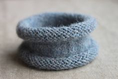 two blue knitted pots sitting on top of a table