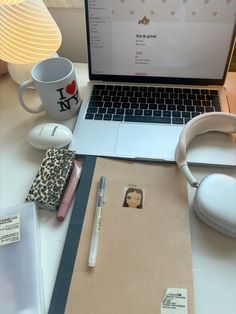 an open laptop computer sitting on top of a desk next to a notepad and headphones