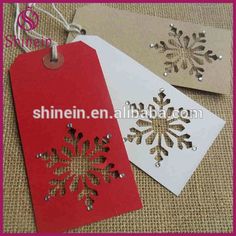 two tags with snowflakes on them are sitting next to each other, one is red and the other is white