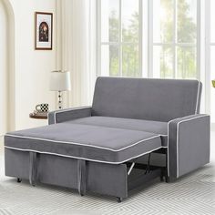 a grey couch with pull out bed underneath it in a living room area next to a window