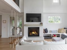 a living room filled with white furniture and a fire place in the middle of it