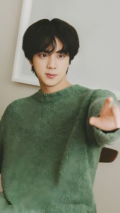 a young man in a green sweater is holding his hand out