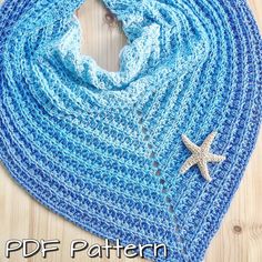 a blue crocheted scarf with a starfish on the side and a wooden background